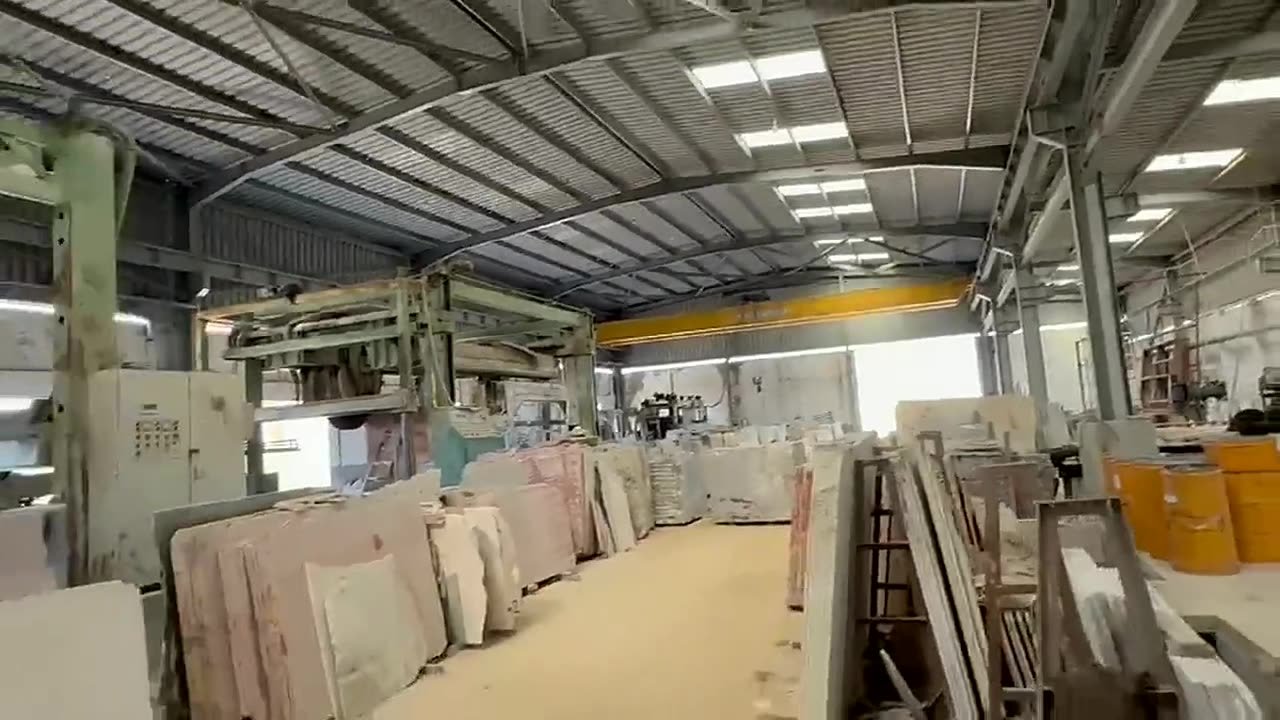 Covered hall at the Wesha Stones factory in Alexandria, with the overhead travelling crane, saw lines and finished slabs on racks